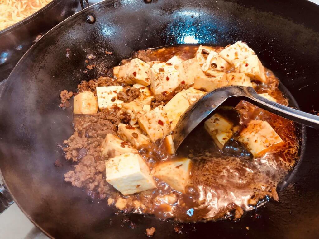 ひき肉を炒めていたフライパンに、豆腐が投入された様子