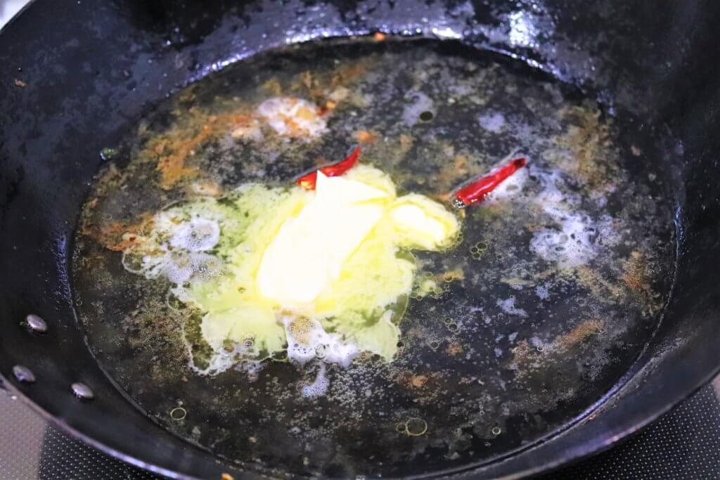 フライパンの余分な油をふき取り、半分に折った鷹の爪１本、白ワイン、バター、レモン汁を加えて、底のこげをこそげとる。