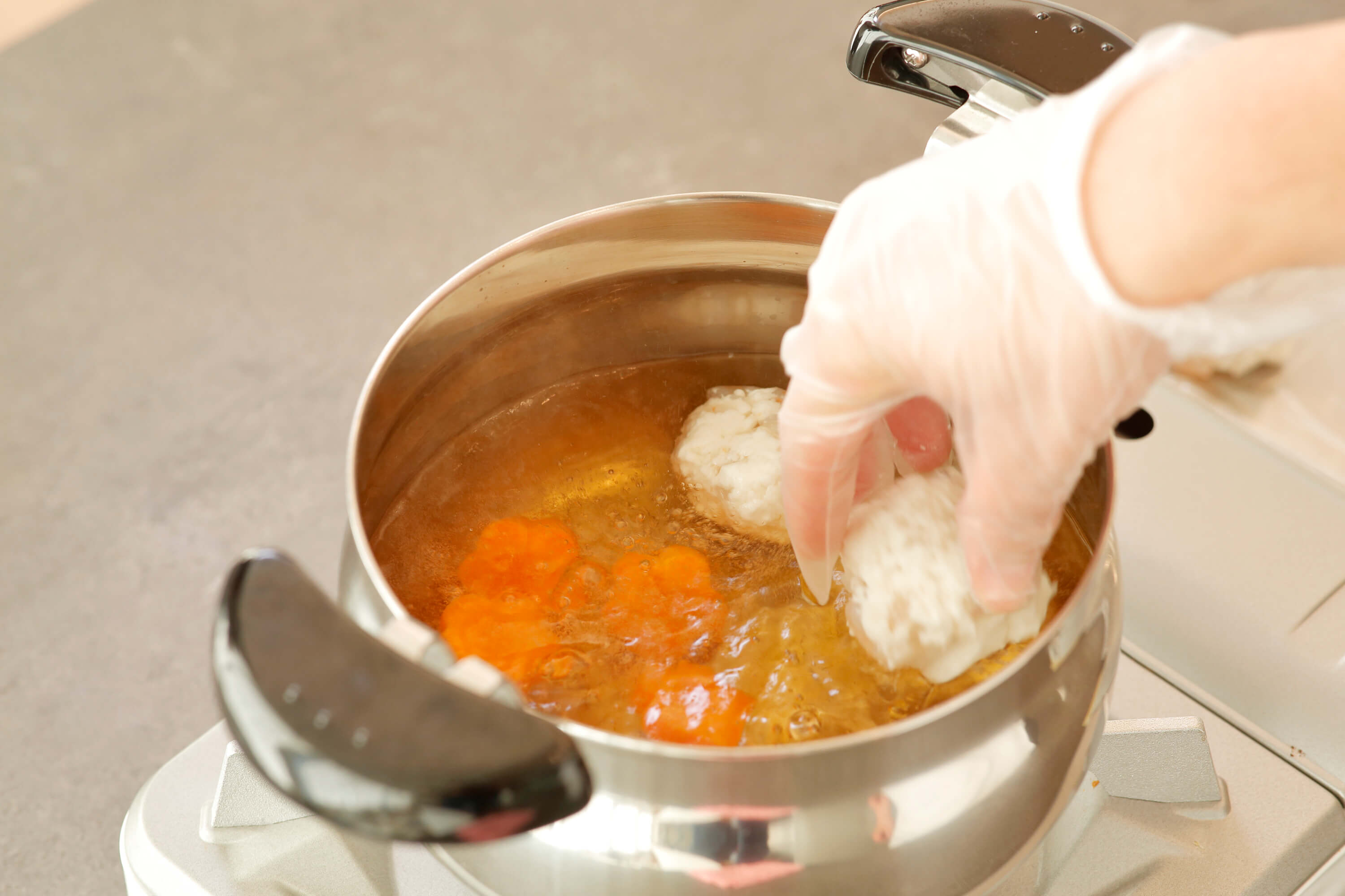 鍋で白だしをお吸い物程度に希釈し、人参を入れ、沸騰したら（1）を直径3cmほどの大きさに丸めて入れる