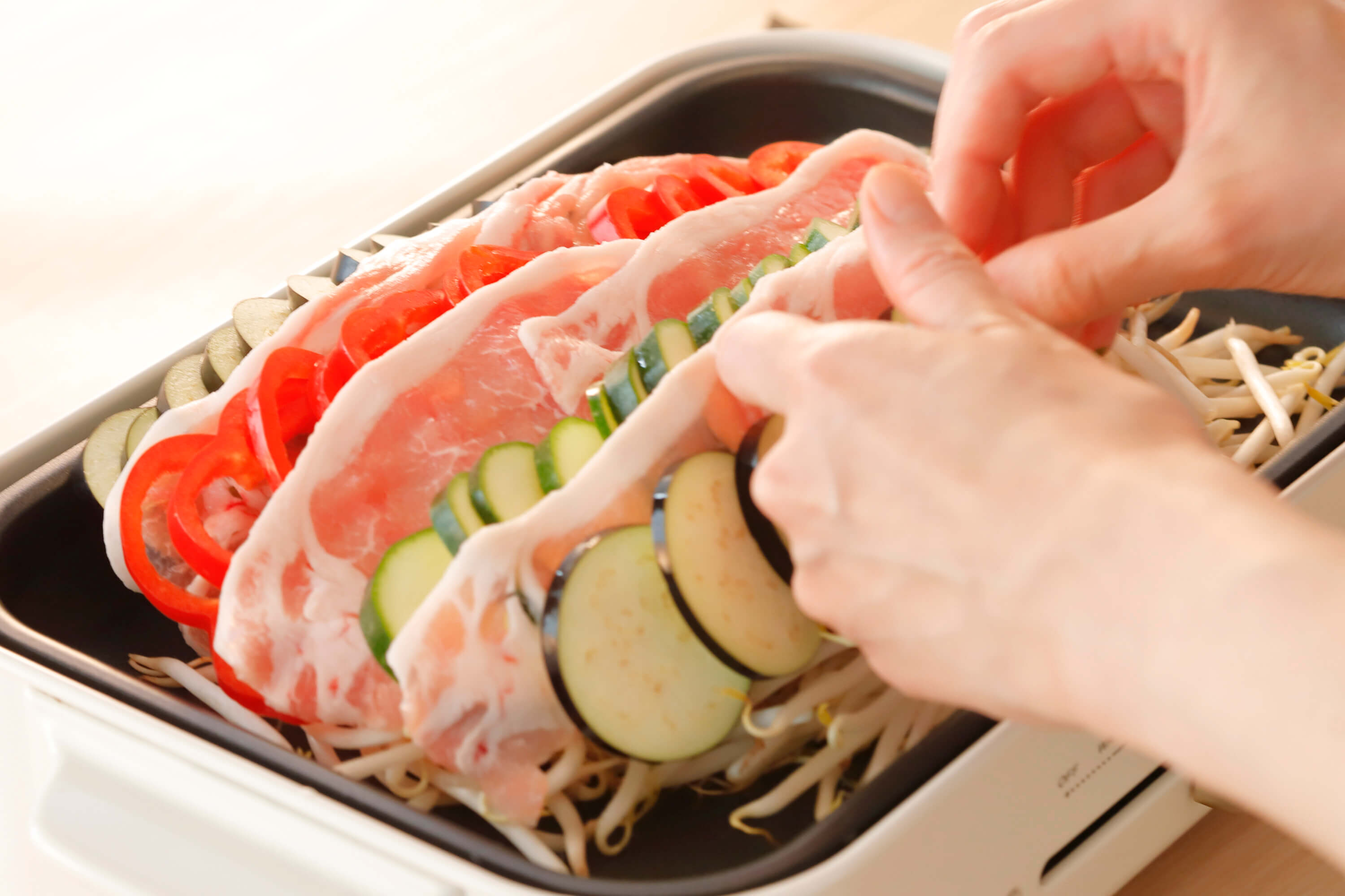 ホットプレートの両端を残してもやしを広げ、2の野菜と豚ロースしゃぶしゃぶ肉を交互になるように重ねる。